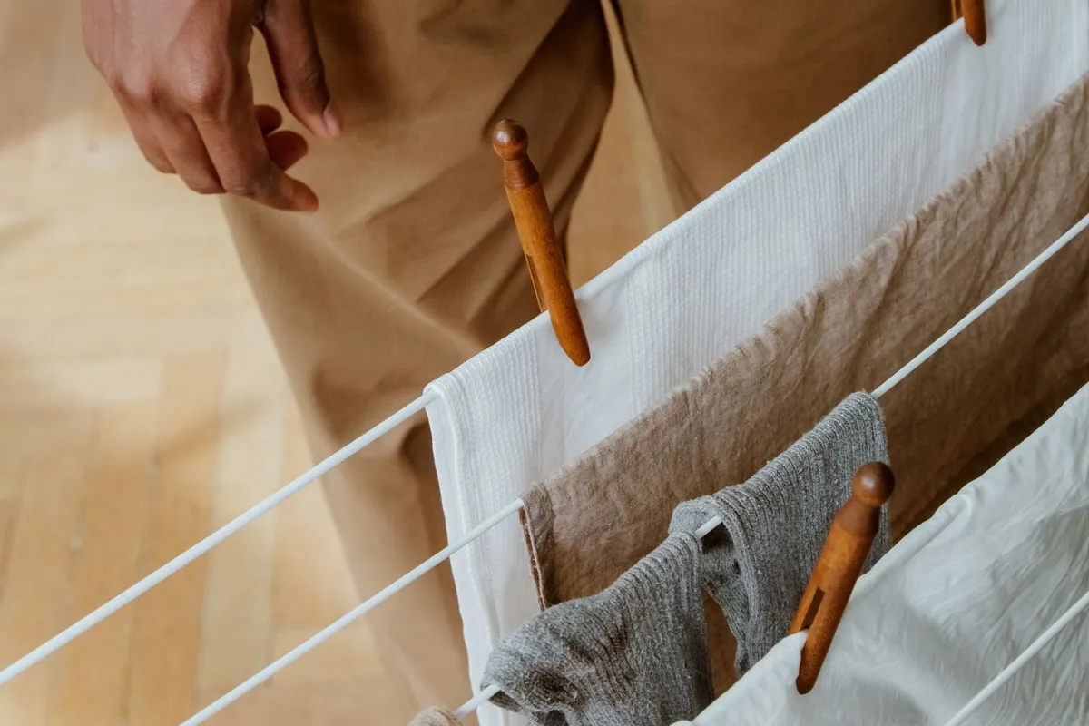 White clothes drying rack with towels and socks hanging on it indoors