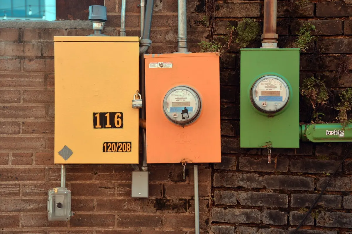 Three electric meters in yellow, orange and green boxes on a brick wall in Texarkana, Texas