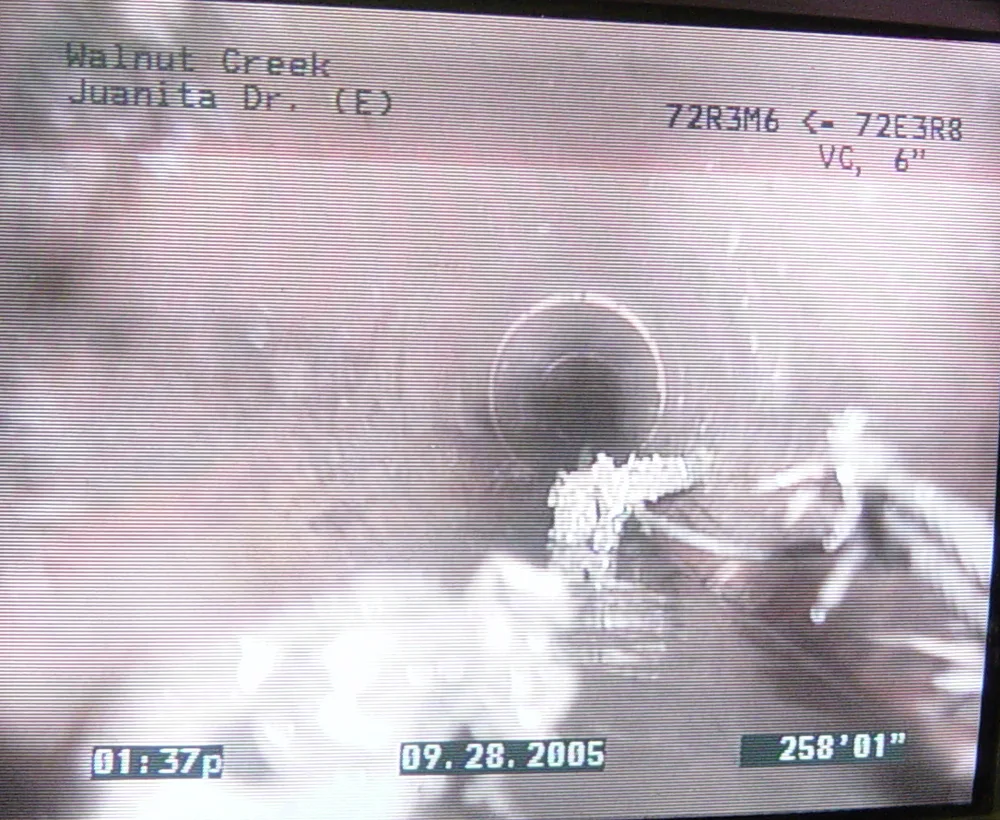 Monitor showing the view from a sewer inspection camera looking down a 6-inch pipe, with on-screen text giving the street, the pipe type and the distance