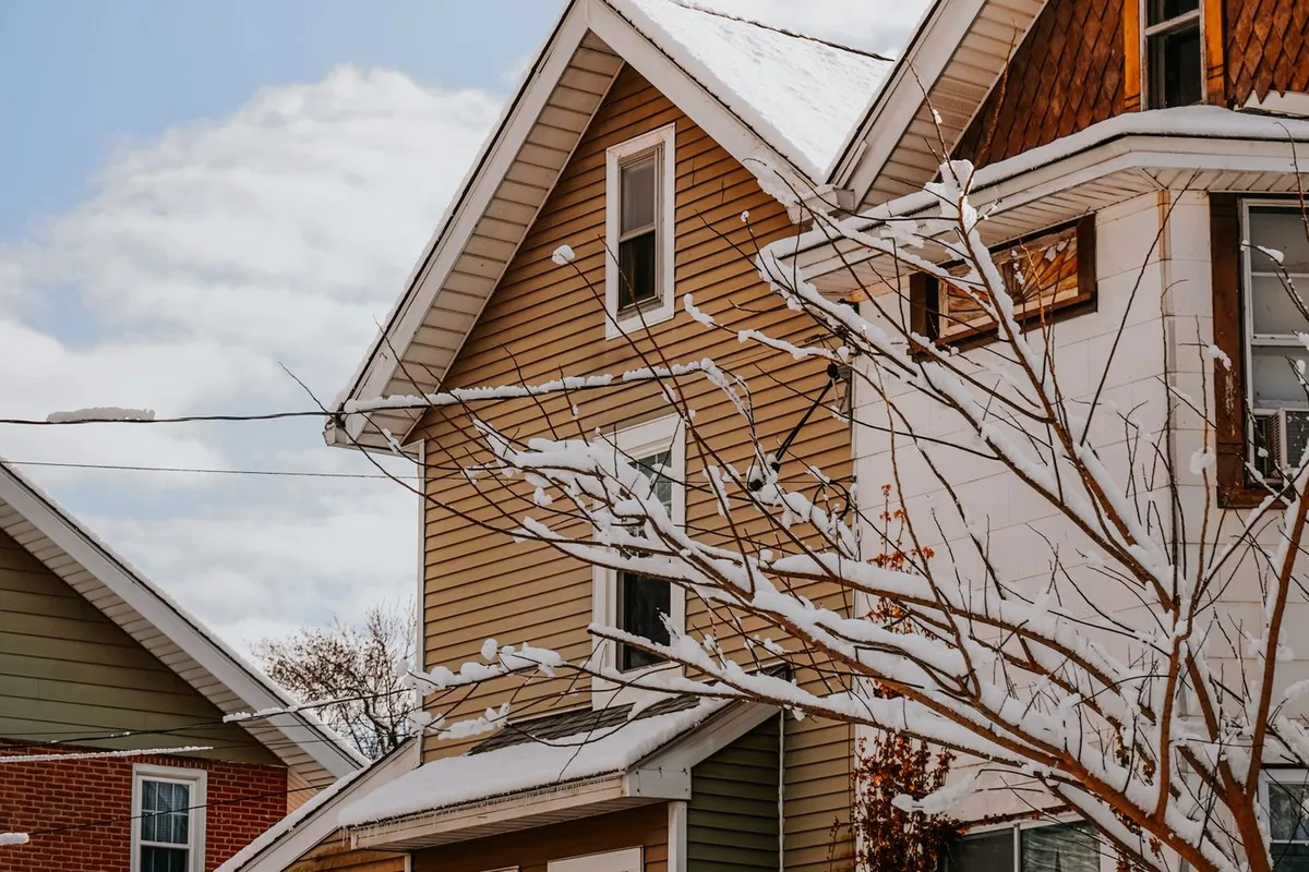 Snow-covered roofs and tree branches on suburban houses in winter