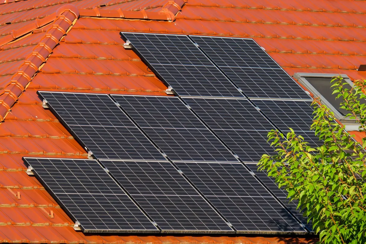 Close-up of rows of dark solar panels mounted on an orange tile roof